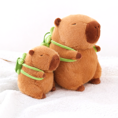 Two Capybara Dreams plush backpack toys of different sizes, both with cute green turtle designs, sitting side-by-side on a white background, demonstrating size variants.