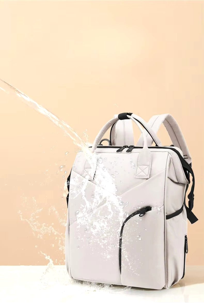 Cloudscape Modern Diaper Backpack in light grey, with water splashing across its surface, highlighting its waterproof and durable material.