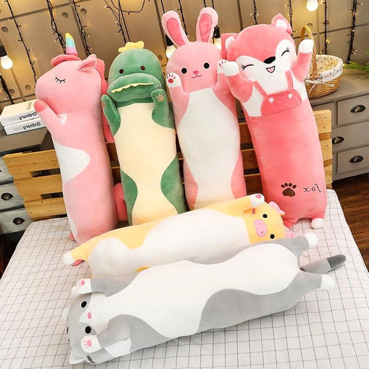 Cuddle Haven collection of long plush toys, including a pink fox, pink bunny, green dinosaur, pink unicorn, gray cat, yellow cat, displayed together on a bed. Showcases various soft fabric animal plushies.
