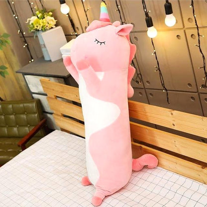 Cuddle Haven Pink Unicorn Plush Toy, a long soft fabric stuffed animal with a huggable design, standing upright on a bed. An adorable stuffed animal cozy plush toy. Measures 35 inches (90 cm).