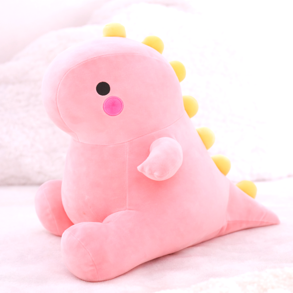 Pink dinosaur plush toy with yellow spikes, soft fabric, adorable features, black eyes, and pink cheeks, sitting on a white textured background. Cute dino stuffed animal.