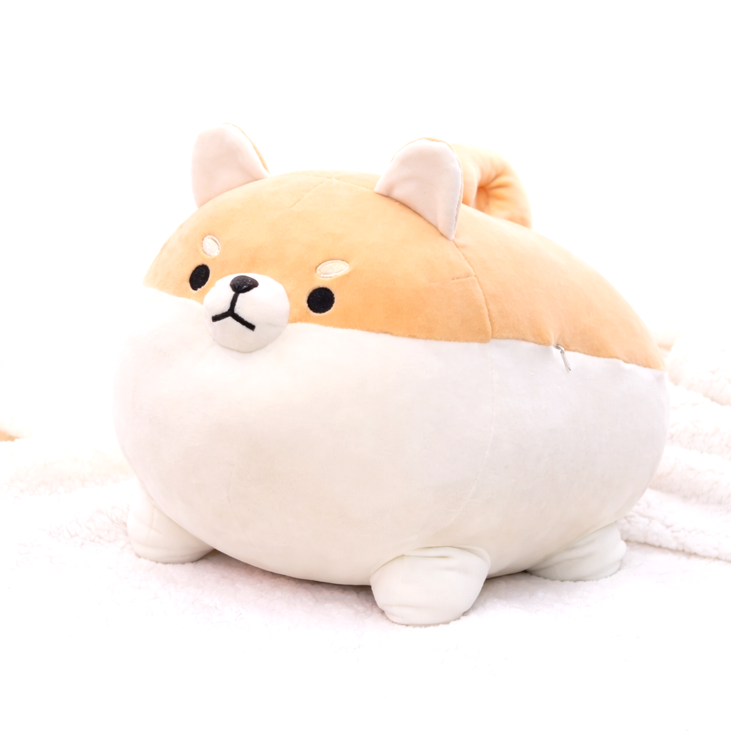 Close-up of a single brown and white Shiba Inu plush toy on a soft white fluffy blanket. Adorable kawaii dog plushie.